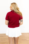Back of Red polo shirt worn by a person on a white background